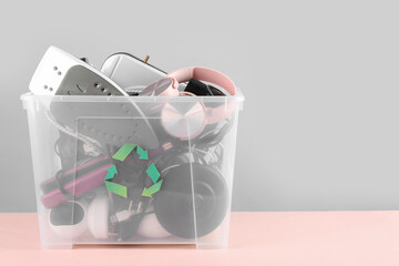 Recycle bin with different household appliances on pink background