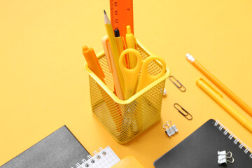 Cup with different school stationery on orange background, closeup