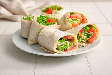 Plate of tasty lavash rolls with tomatoes and greens on white tile background