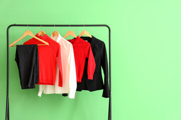 Stylish school uniform hanging on rack near green wall in room