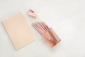 Notebook with pens and pencils holder on beige background