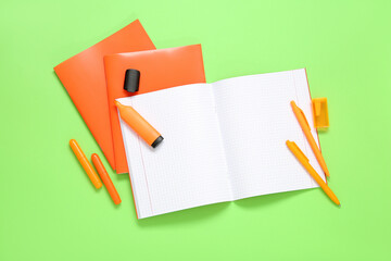 Orange notebooks with markers on green background