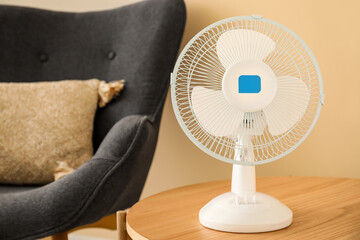 Wooden coffee table with modern electric fan in interior of living room