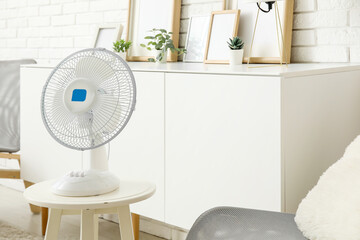 Modern electric fan on table in interior of living room