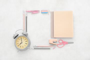 Alarm clock with different stationery on beige background