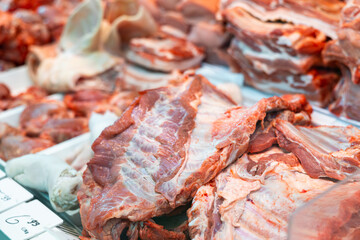 Slabs of raw pork ribs arranged in refrigerated butchery shop display case. Fresh meat products