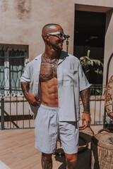 Chico joven tatuado y musculoso posando en piscina de hotel en un día soleado de verano 