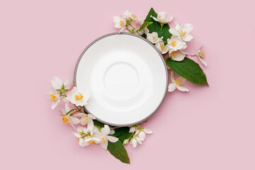 Composition with plate and beautiful jasmine flowers on pink background
