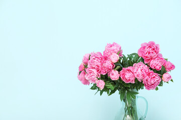 Vase of pink peonies on blue background