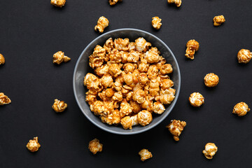 Bowl with tasty popcorn on black background