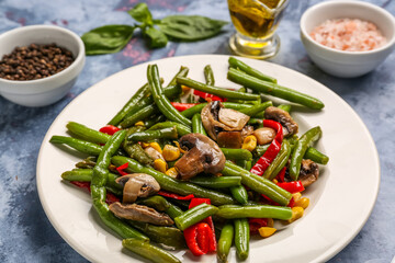 Plate with different vegetables on blue background