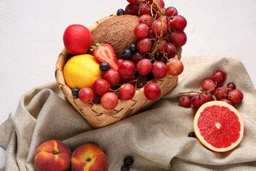 Wicker basket with different fresh fruits on white background