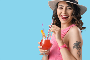 Young woman in summer hat with cocktail on blue background, closeup