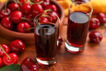 Shots with sweet cherry liqueur and bowl with fresh berries on wooden table