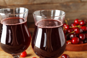 Glasses with sweet cherry liqueur on wooden background