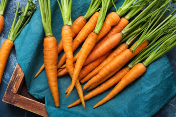 Wooden board of fresh carrots on blue textured background