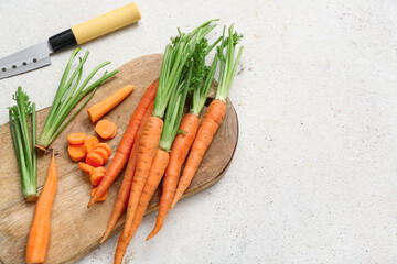 Fresh carrots and wooden board on white grunge background