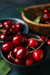 Bowls with sweet cherries on blue background, closeup