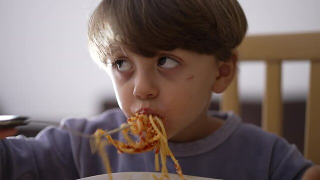 Child eating pasta. Little kid eats spaghetti with fork by himself