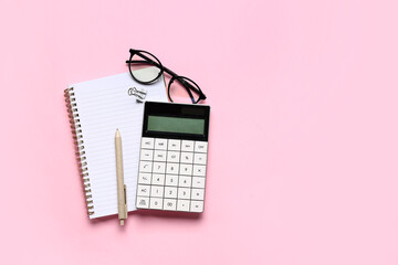 Modern calculator with eyeglasses and stationery on pink background