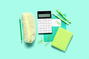 Modern calculator with stationery on turquoise background