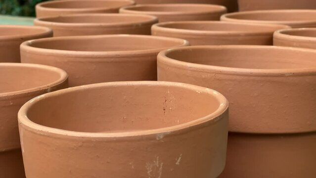 New clay flower pots stand in rows on the shelves of a floriculture store. Close up