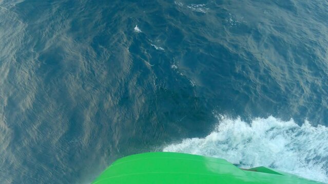 Splashes and wave from bow of ship. Top down bow view. Green side vessel. Spray from bow of the vessel