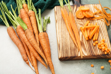 Fresh carrots and wooden board with slices on white background