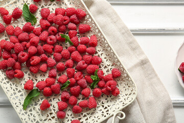 Tray with fresh raspberries and mint on white background