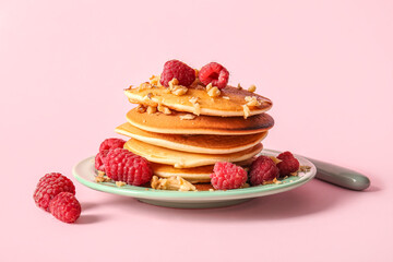 Plate of tasty pancakes with raspberries on pink background