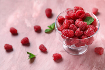 Glass bowl with fresh raspberry and mint on pink background, closeup