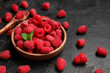 Wooden bowl with fresh raspberry and mint on dark background, closeup