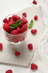 Glass with fresh raspberry and mint on light background, closeup