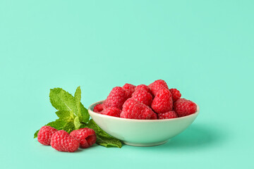 Bowl with fresh raspberries and mint on turquoise background