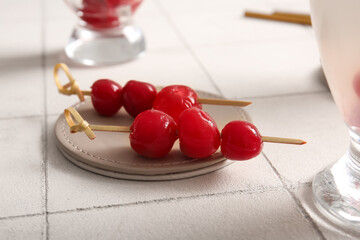 Tasty maraschino cherries on white tile background