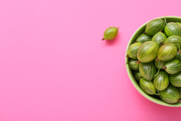 Bowl with fresh gooseberry on pink background, closeup