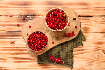 Bowls with fresh red currant on wooden background