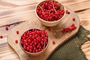 Bowls with fresh red currant on wooden background, closeup