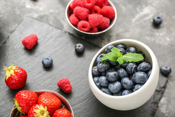 Bowls with different fresh berries on grey background, closeup