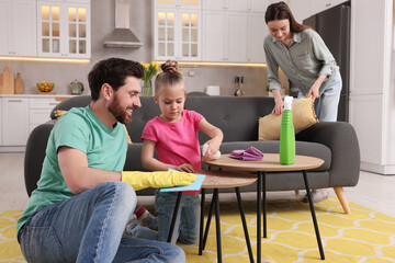 Spring cleaning. Parents with their daughter tidying up living room together