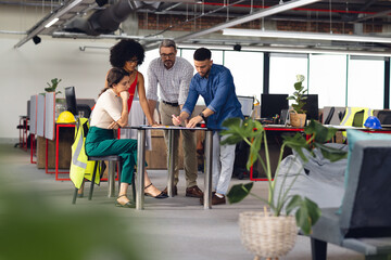 Diverse casual business people looking at architectural plans and discussing work at office