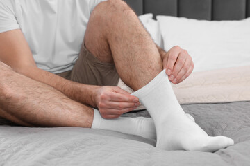 Man putting on white socks at home, closeup