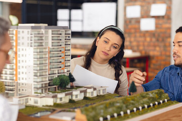 Diverse business people looking at architectural model and discussing work at office