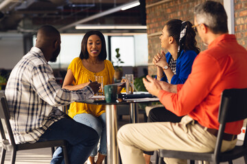 Diverse business people sitting at table, having meeting and discussing work at office