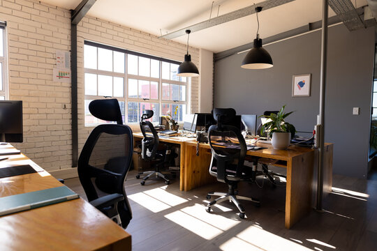 Sunny, modern casual office interior with desks, computers and big window, copy space