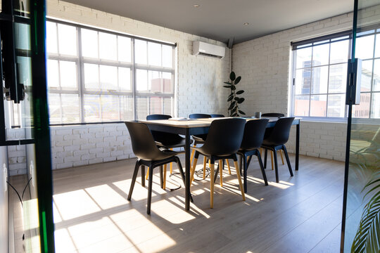 Sunny modern office meeting room interior with table, chairs and big windows, copy space
