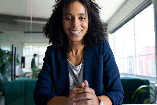 Happy biracial casual businesswoman in office having video call, smiling