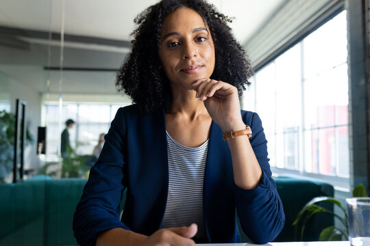 Happy biracial casual businesswoman in office having video call, listening