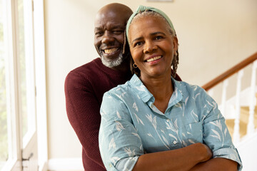 Portrait of happy senior african american couple smiling and embracing in hallway