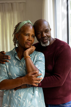 Thoughtful african american senior couple embracing and talking, looking out of window